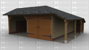 An oak frame garage with 2 bays split into an open area and an enclosed one with barn doors. This building has a low pitched roof and an aisle down the right hand side.