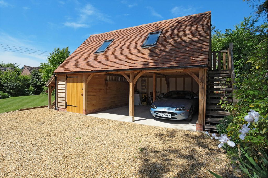 a two bay wooden garage made of oak with a sports car